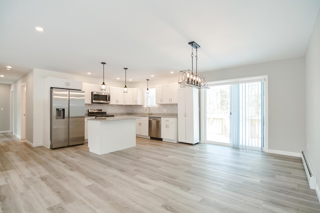 kitchen featuring appliances with stainless steel finishes, white cabinetry, a center island, tasteful backsplash, and decorative light fixtures