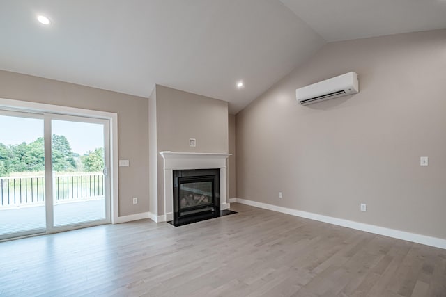 unfurnished living room with vaulted ceiling, light hardwood / wood-style floors, and an AC wall unit