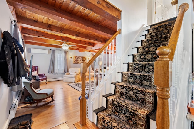 stairs with wood ceiling, a baseboard heating unit, beam ceiling, a wall mounted AC, and wood-type flooring