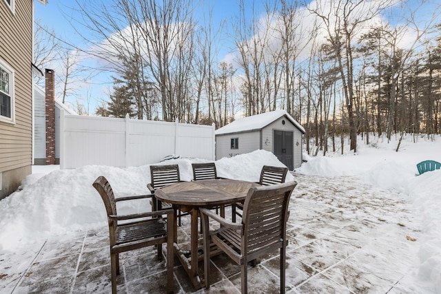 snow covered patio with a storage shed