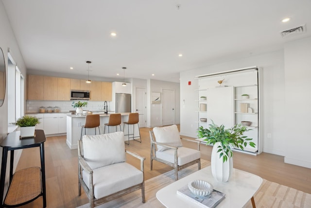 living area with visible vents, baseboards, light wood finished floors, and recessed lighting