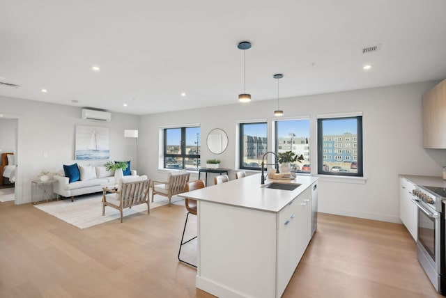 kitchen with visible vents, a sink, appliances with stainless steel finishes, a wall mounted AC, and light wood finished floors