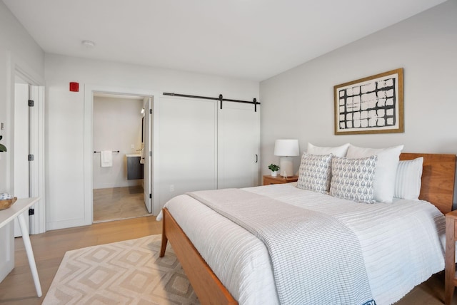bedroom with a barn door and light wood-style floors
