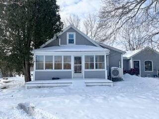 snow covered rear of property featuring ac unit