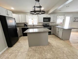 kitchen with white cabinetry, hanging light fixtures, a center island, black appliances, and beamed ceiling