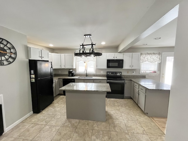 kitchen featuring decorative light fixtures, sink, a center island, light stone counters, and black appliances