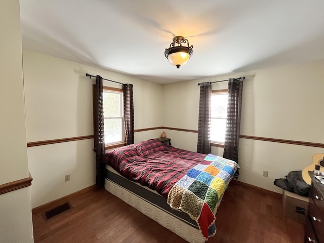 bedroom with dark hardwood / wood-style floors and multiple windows