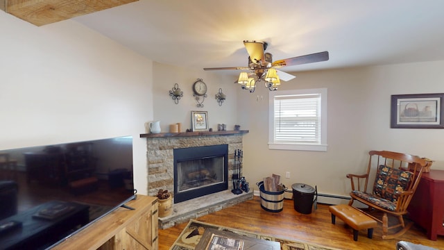 living room with a stone fireplace, wood-type flooring, ceiling fan, and baseboard heating