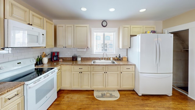 kitchen featuring sink, light hardwood / wood-style flooring, white appliances, cream cabinetry, and backsplash