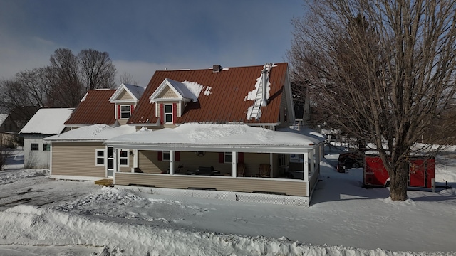 snow covered rear of property featuring covered porch