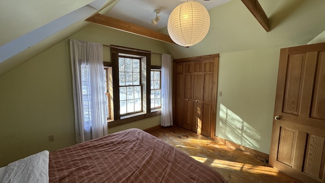 unfurnished bedroom with vaulted ceiling with beams and a closet