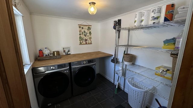 clothes washing area featuring ornamental molding, washing machine and clothes dryer, and dark tile patterned flooring