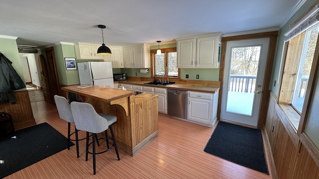 kitchen with pendant lighting, dishwasher, butcher block counters, sink, and white fridge