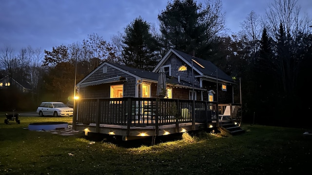 back house at dusk with a wooden deck and a yard