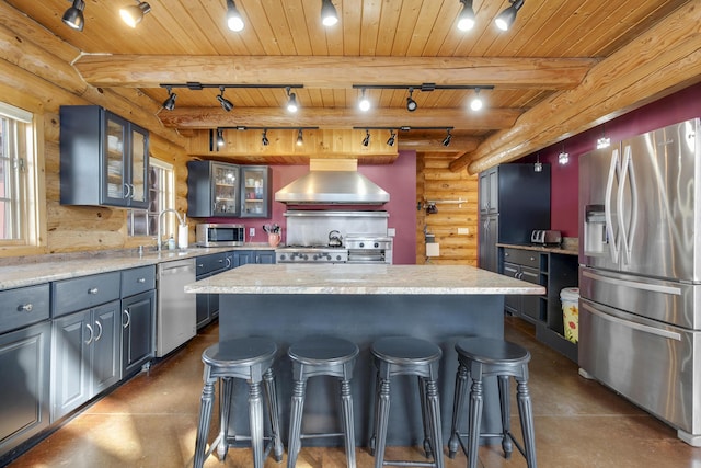 kitchen featuring wall chimney exhaust hood, appliances with stainless steel finishes, a center island, and wooden ceiling