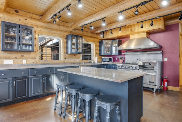 kitchen with stainless steel appliances, a center island, light stone countertops, wooden ceiling, and wall chimney exhaust hood