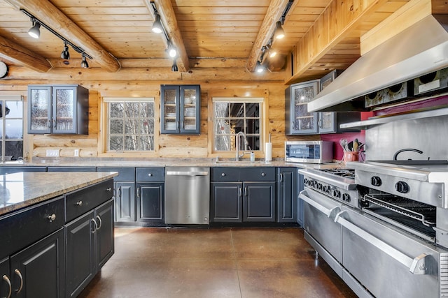 kitchen with rail lighting, sink, light stone counters, appliances with stainless steel finishes, and range hood