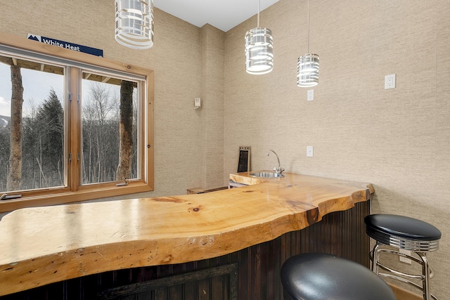 bar featuring pendant lighting, sink, and wood counters