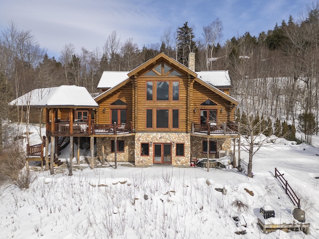 snow covered back of property featuring a deck