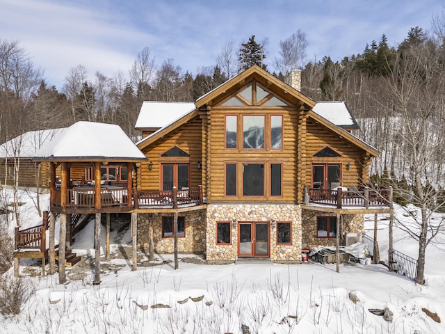 snow covered rear of property with a deck