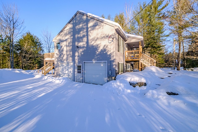 view of snowy exterior featuring a wooden deck and a garage