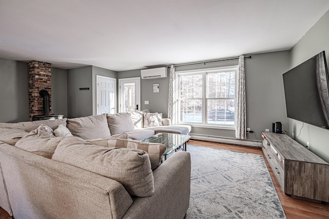 living room featuring a wood stove, a wall mounted air conditioner, baseboard heating, and light wood-type flooring