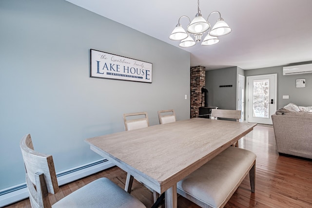 dining space with hardwood / wood-style floors, a baseboard radiator, a wall unit AC, and a wood stove