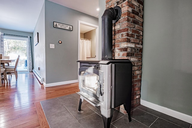 interior details with a baseboard heating unit, hardwood / wood-style flooring, and a wood stove