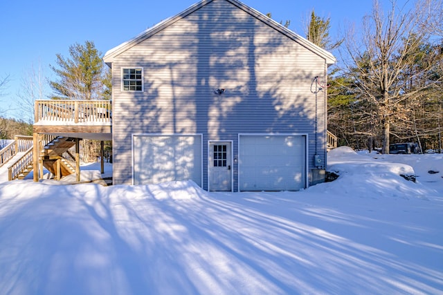 view of snowy exterior with a garage and a deck