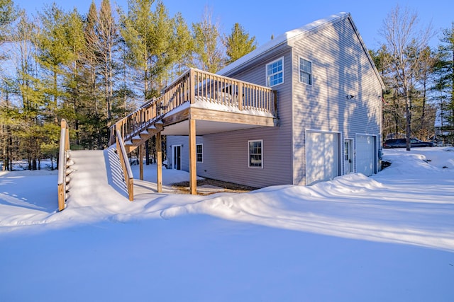 snow covered property featuring a wooden deck and a garage