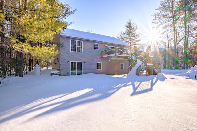 snow covered house featuring a wooden deck