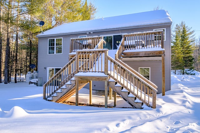 snow covered rear of property with a deck