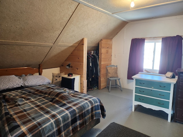 bedroom featuring lofted ceiling, concrete flooring, and a closet