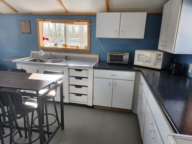 kitchen featuring a kitchen bar, sink, and white cabinets