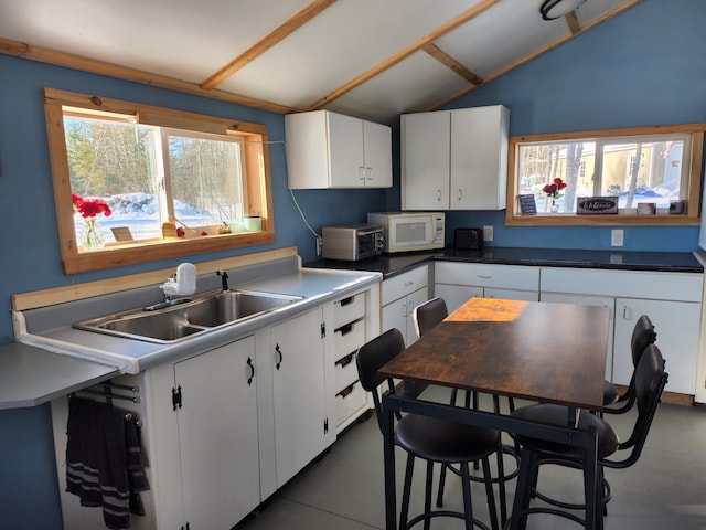 kitchen with white cabinetry, lofted ceiling, and sink