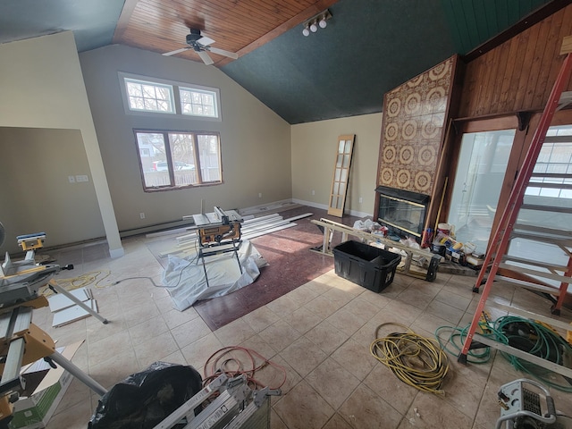 living room with light tile patterned floors, ceiling fan, track lighting, high vaulted ceiling, and a tile fireplace