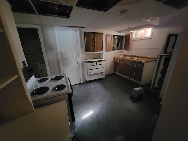 kitchen featuring a drop ceiling, brown cabinets, light countertops, concrete floors, and range with electric stovetop