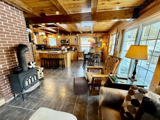 living room with wood walls, wood ceiling, a wood stove, dark tile patterned floors, and beamed ceiling