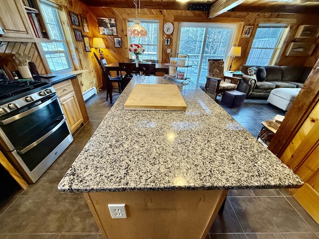 kitchen with gas range, a wealth of natural light, a kitchen island, and wood walls