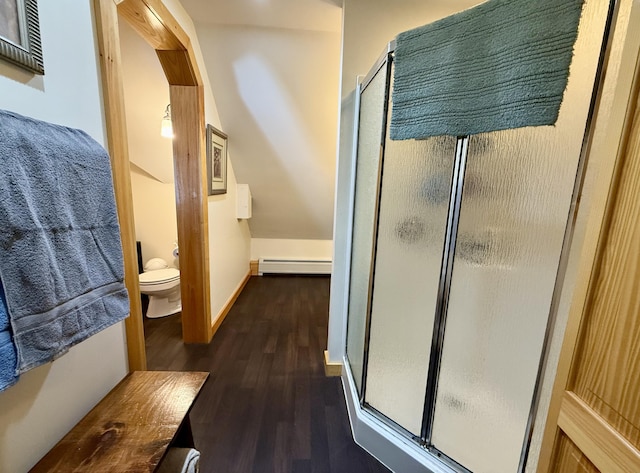 bathroom with walk in shower, toilet, wood-type flooring, vaulted ceiling, and a baseboard heating unit