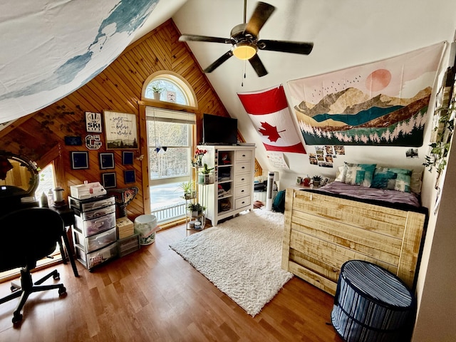 bedroom featuring hardwood / wood-style flooring, vaulted ceiling, ceiling fan, and wood walls