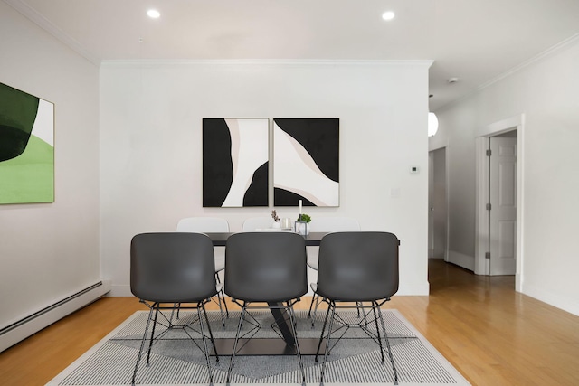 dining space with hardwood / wood-style flooring, a baseboard heating unit, and ornamental molding