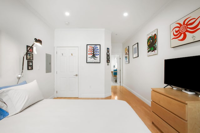 bedroom with electric panel, crown molding, and hardwood / wood-style floors