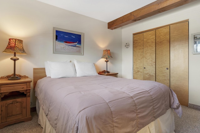 carpeted bedroom with beam ceiling and a closet