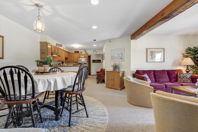 carpeted dining space featuring beamed ceiling and a textured ceiling