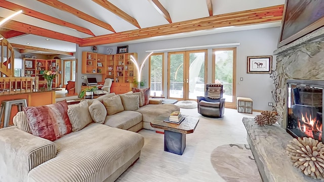 living area with beam ceiling, french doors, and a stone fireplace