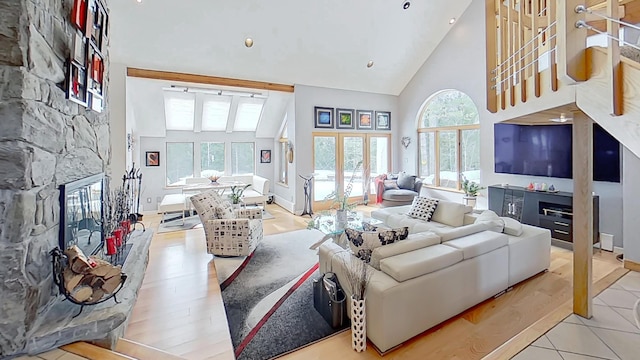 tiled living area featuring stairway, baseboards, high vaulted ceiling, and a stone fireplace