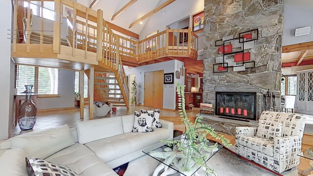 living area with high vaulted ceiling, tile patterned flooring, a fireplace, stairway, and beam ceiling