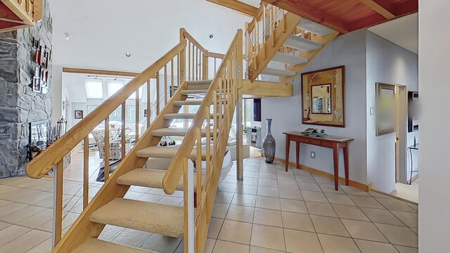 stairs featuring tile patterned flooring, high vaulted ceiling, and beamed ceiling