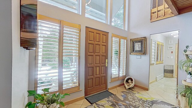 foyer with a wealth of natural light, a towering ceiling, baseboards, and tile patterned floors